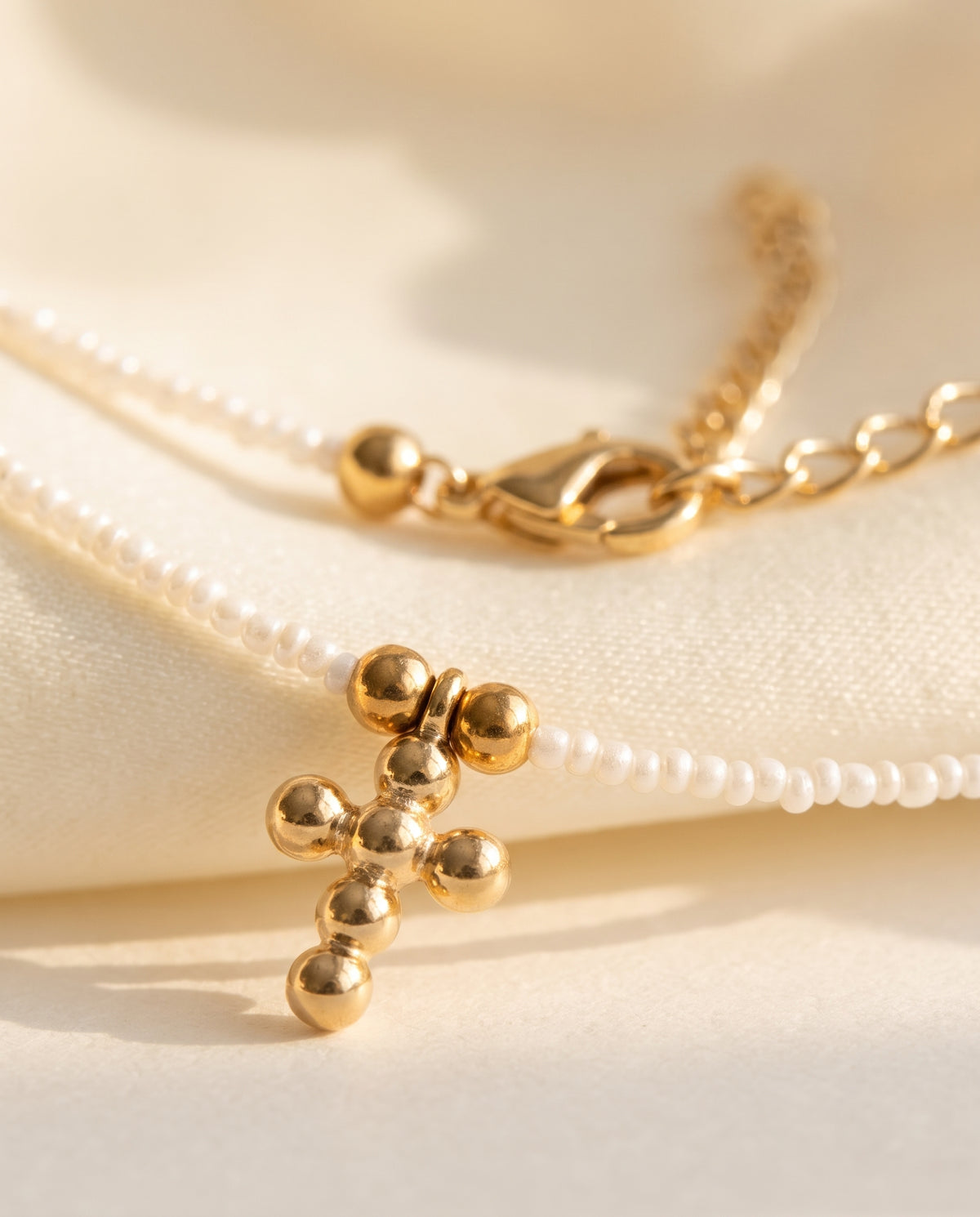 Detalle de la cruz de chapa de oro y las perlas naturales del collar Perla Santa