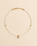 Collar de perla natural blanca con cruz de chapa de oro sobre fondo crema, Perla Santa