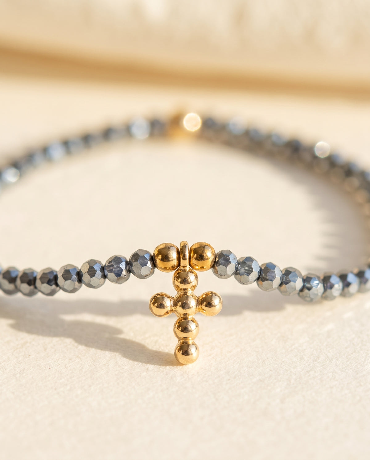 Detalle de la cruz de chapa de oro y las cuentas de cristal facetado de la pulsera Perla Santa